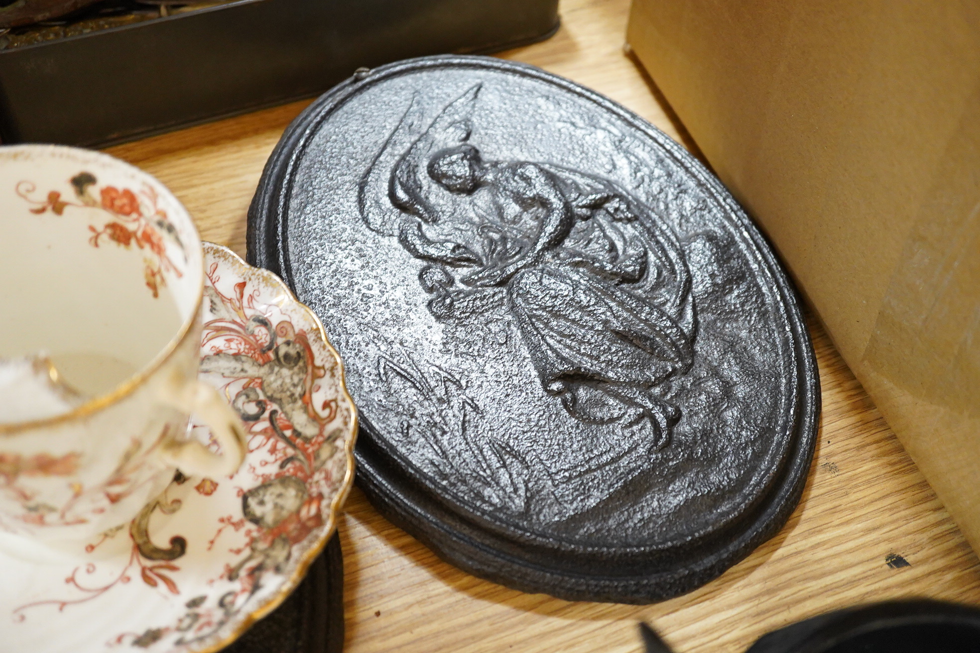 Two framed pot lids, two oval figural plaques,a moustache cup and saucer, two Bretby cats, framed print and mixed nut crackers cutlery etc